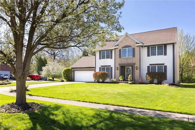 colonial house featuring roof with shingles, an attached garage, driveway, and a front yard