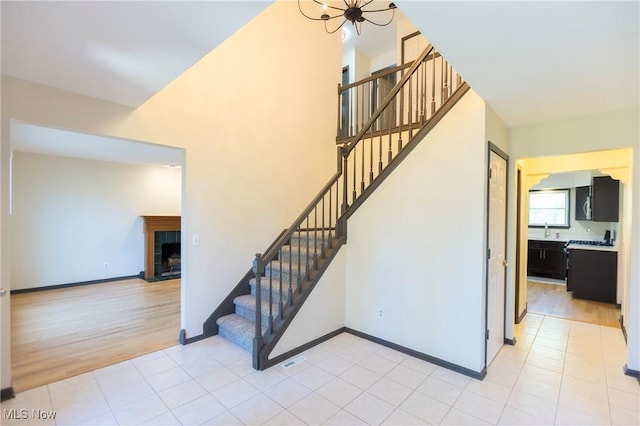 stairway with an inviting chandelier, tile patterned flooring, baseboards, and a tiled fireplace