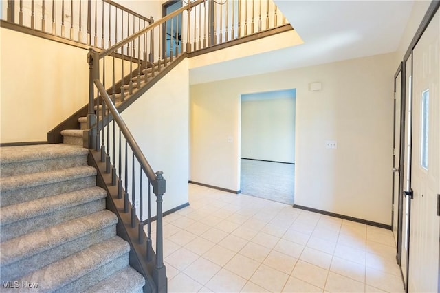 stairway featuring baseboards, carpet floors, and tile patterned floors
