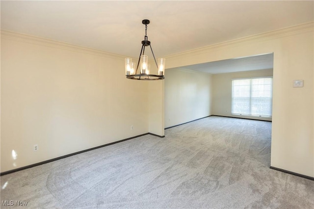 spare room featuring crown molding, baseboards, a chandelier, and carpet floors