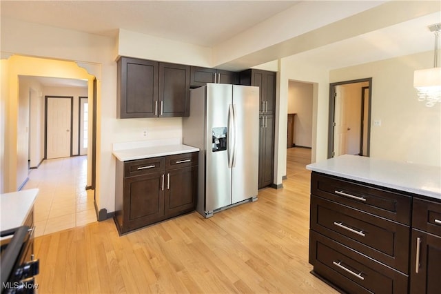kitchen featuring dark brown cabinetry, light wood finished floors, light countertops, decorative light fixtures, and stainless steel refrigerator with ice dispenser