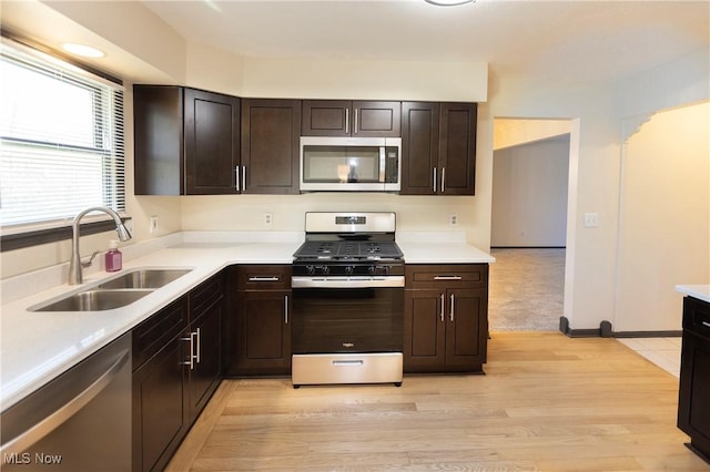 kitchen featuring light countertops, stainless steel appliances, dark brown cabinetry, and a sink