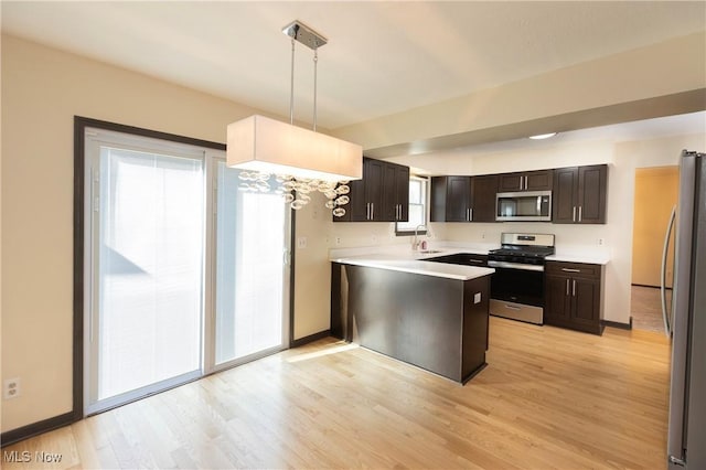 kitchen with hanging light fixtures, light wood-type flooring, dark brown cabinets, light countertops, and stainless steel appliances