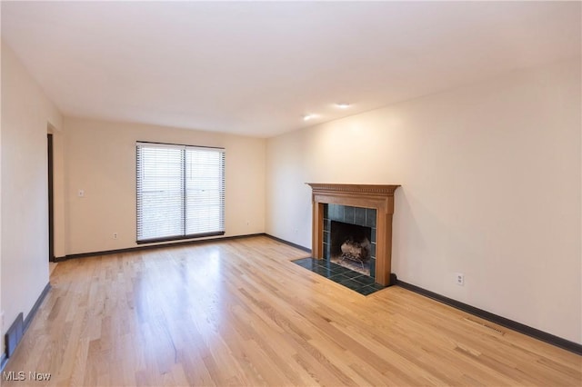 unfurnished living room featuring light wood-style floors, baseboards, visible vents, and a tile fireplace
