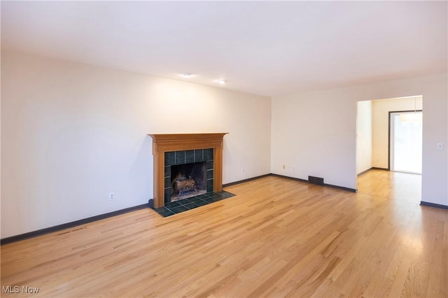 unfurnished living room featuring a fireplace, baseboards, visible vents, and light wood-style floors