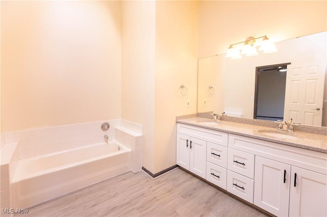 bathroom featuring double vanity, a sink, a garden tub, and wood finished floors
