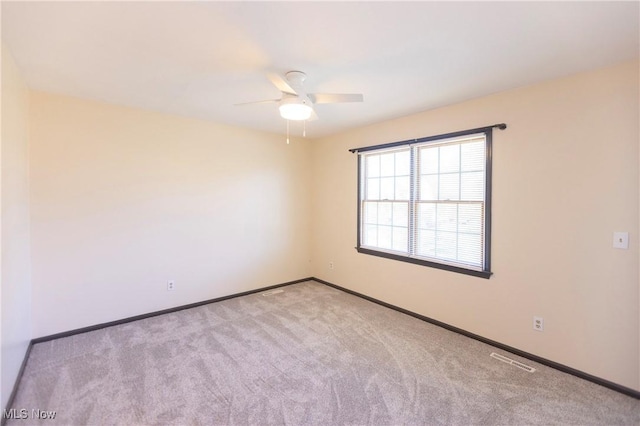 carpeted empty room featuring visible vents, a ceiling fan, and baseboards