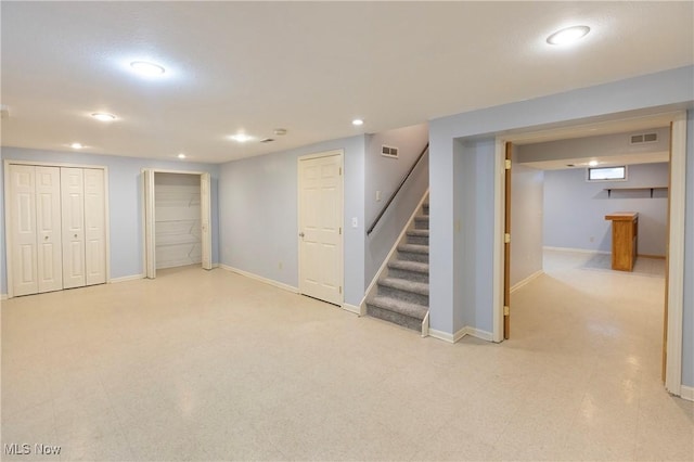 finished below grade area with visible vents, recessed lighting, baseboards, and stairway