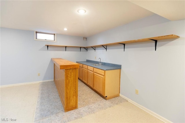 kitchen with dark countertops, open shelves, a sink, baseboards, and recessed lighting