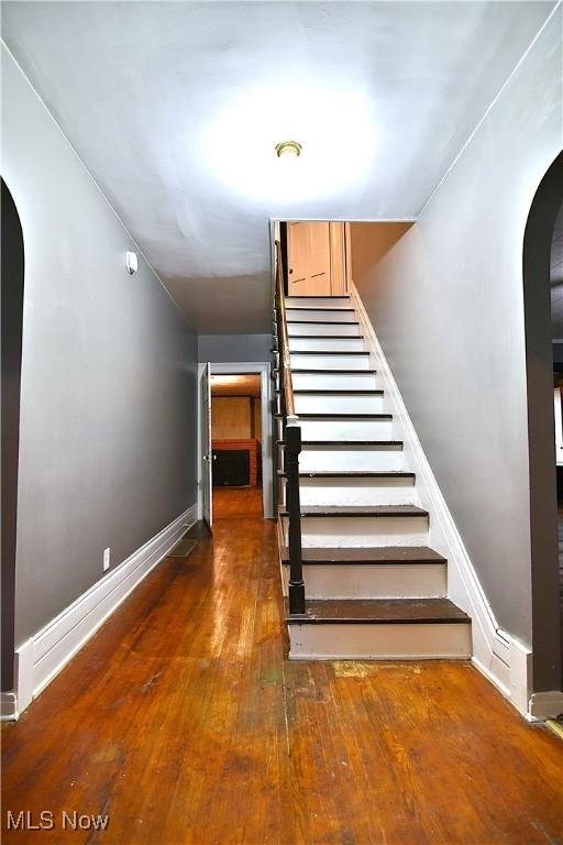11680 Walnut Ave NE, Alliance, OH 44601 - stairs featuring baseboards, arched walkways, and hardwood / wood-style flooring