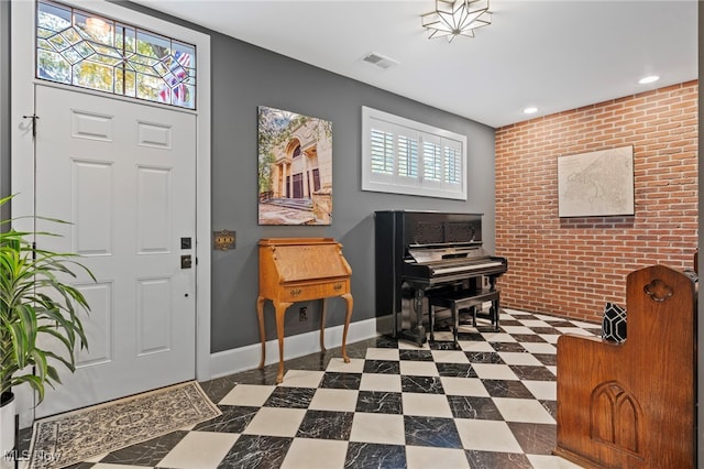 foyer entrance with visible vents, an accent wall, brick wall, baseboards, and recessed lighting