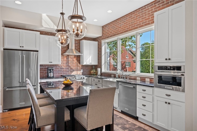 kitchen with a kitchen bar, a sink, dark stone countertops, a chandelier, and stainless steel appliances