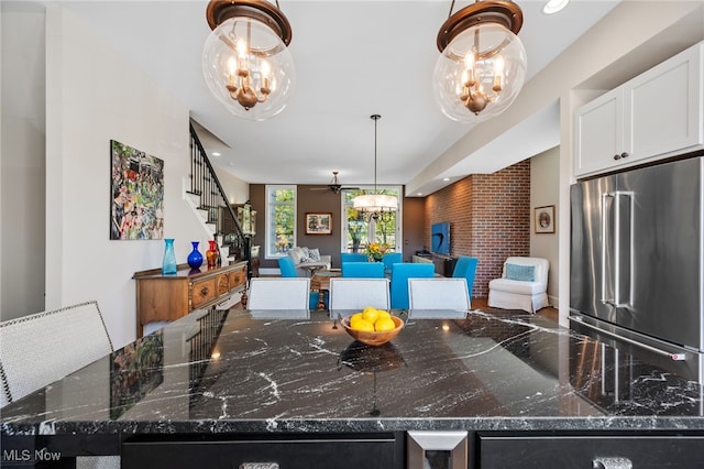 kitchen with open floor plan, high quality fridge, white cabinetry, a ceiling fan, and dark stone countertops