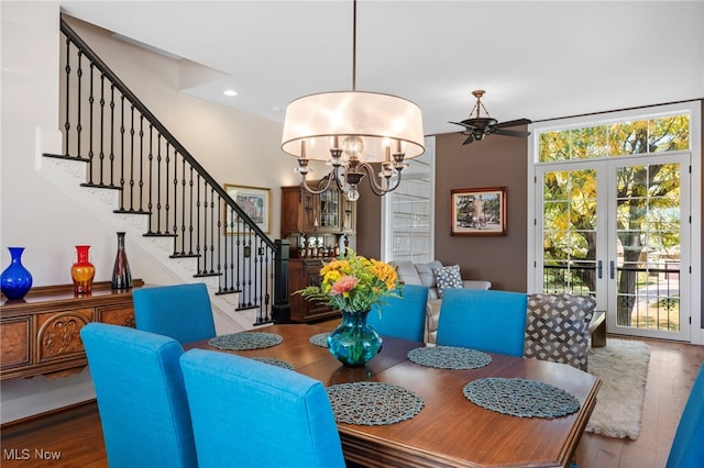 dining space with ceiling fan with notable chandelier, stairs, and wood finished floors
