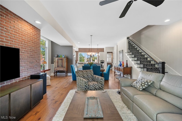 living room featuring light wood-style floors, ceiling fan with notable chandelier, recessed lighting, baseboards, and stairway