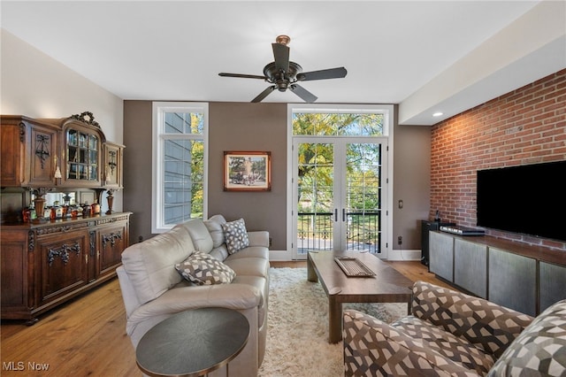 living room featuring plenty of natural light, a ceiling fan, and light wood-type flooring