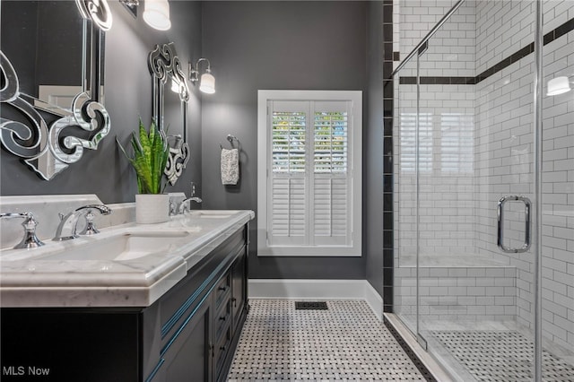 bathroom with baseboards, tile patterned floors, a sink, and a stall shower
