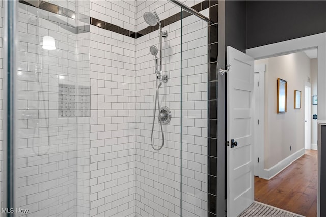 full bath featuring baseboards, a shower stall, and wood finished floors