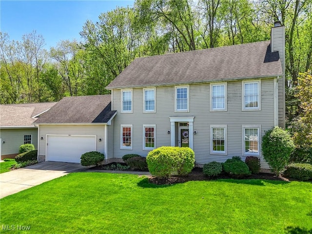 colonial inspired home with a garage, a front yard, a chimney, and concrete driveway