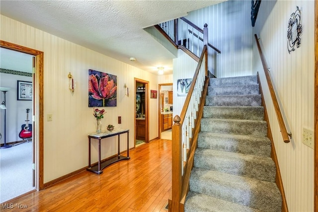 stairs with baseboards, hardwood / wood-style flooring, and a textured ceiling