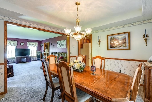 dining space with carpet flooring, wallpapered walls, and a chandelier