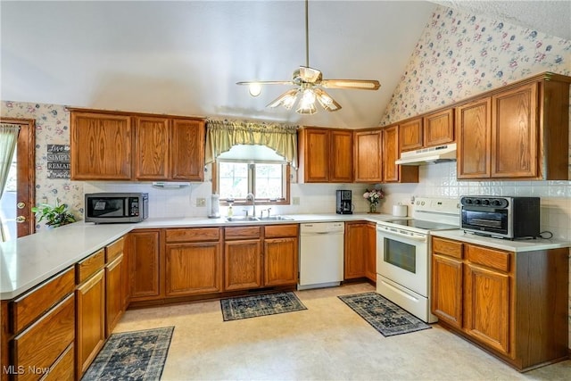 kitchen featuring ceiling fan, a sink, under cabinet range hood, wallpapered walls, and white appliances