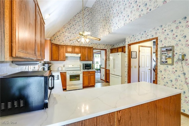 kitchen featuring white appliances, a ceiling fan, wallpapered walls, lofted ceiling, and under cabinet range hood