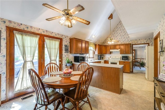 dining room with a ceiling fan, wallpapered walls, visible vents, and vaulted ceiling