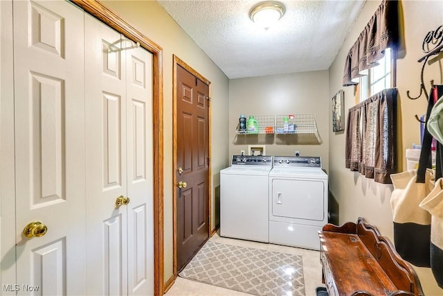 washroom featuring independent washer and dryer, a textured ceiling, and laundry area