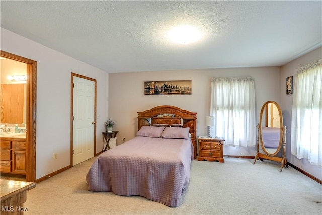bedroom featuring baseboards, carpet, a textured ceiling, and connected bathroom