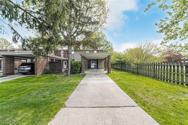view of front of home featuring brick siding, fence, driveway, and a front yard