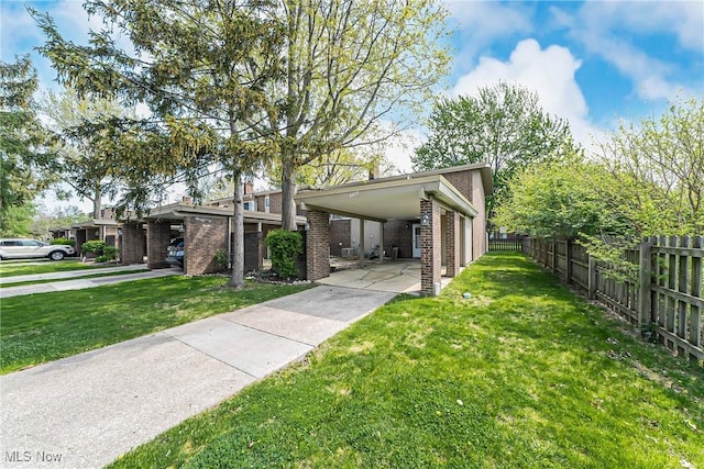view of front of property featuring brick siding, driveway, fence, and a front yard