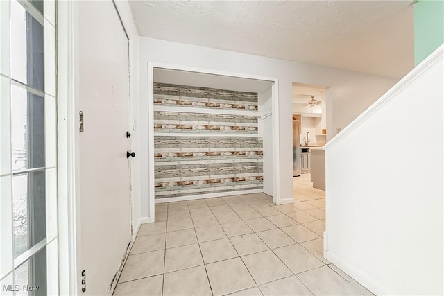 entryway with baseboards, a ceiling fan, light tile patterned floors, and wooden walls