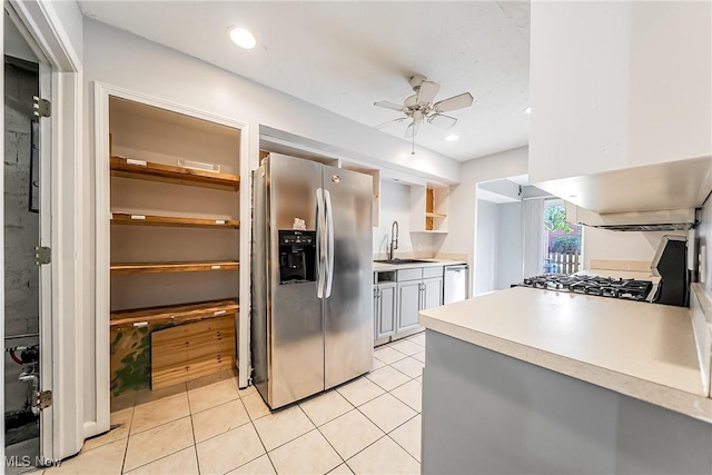 kitchen with ceiling fan, light countertops, a sink, light tile patterned floors, and stainless steel appliances