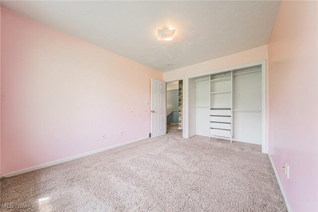 unfurnished bedroom with baseboards, carpet, and a closet