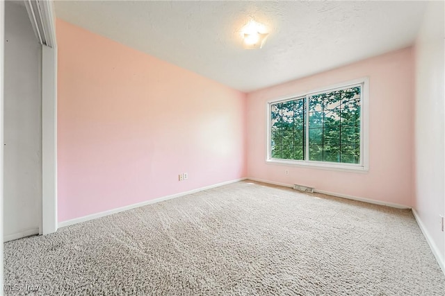 carpeted spare room with baseboards and visible vents