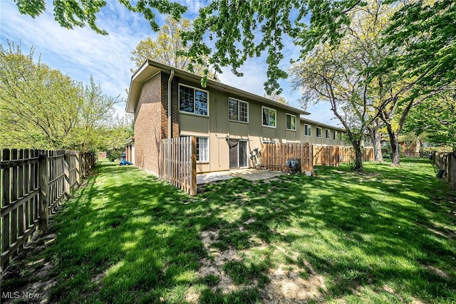 rear view of house featuring brick siding, a fenced backyard, a patio area, and a yard
