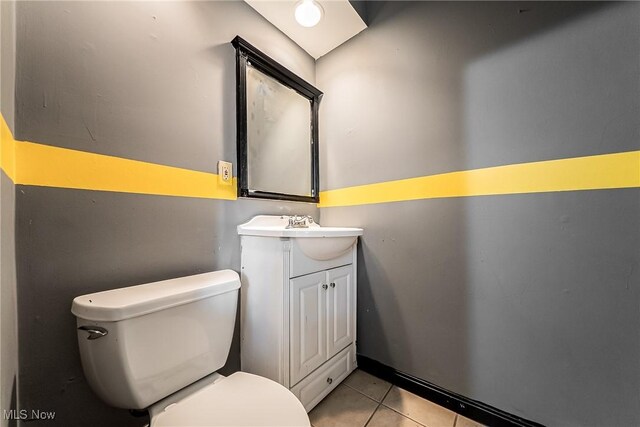 half bath with tile patterned floors, vanity, and toilet