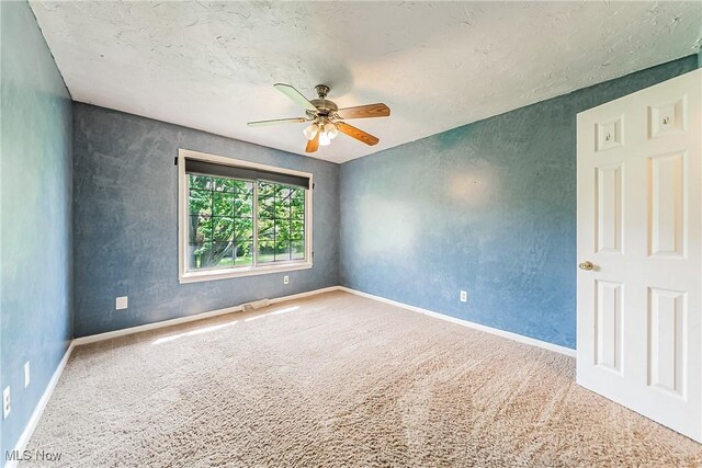 carpeted empty room featuring a ceiling fan, baseboards, visible vents, and a textured ceiling