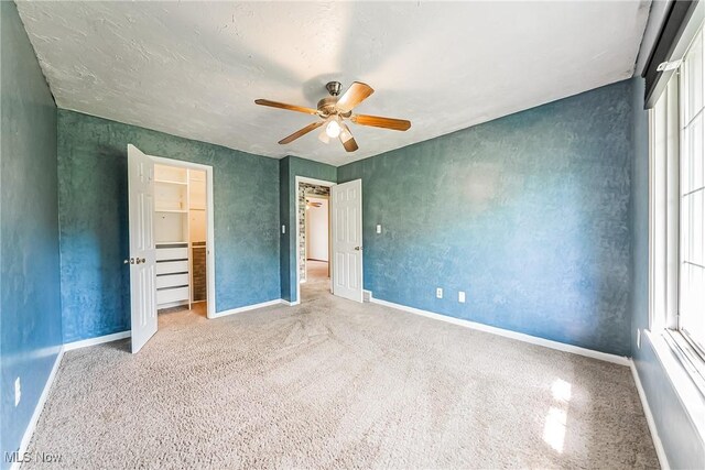 unfurnished bedroom featuring a ceiling fan, baseboards, multiple windows, and a closet