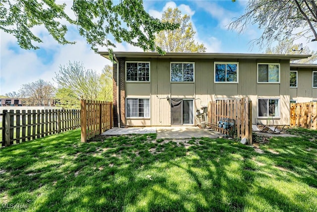 rear view of house with fence, a yard, and a patio area