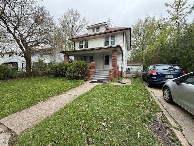 american foursquare style home with a porch and a front lawn