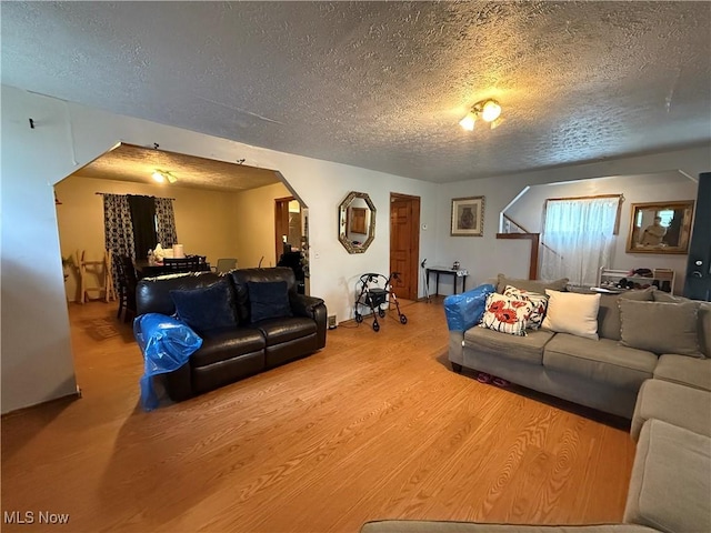 living room featuring arched walkways, a textured ceiling, and wood finished floors