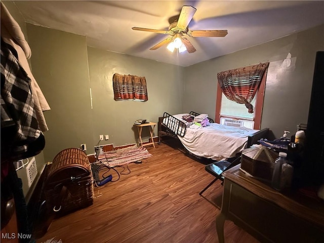 bedroom featuring ceiling fan, wood finished floors, and cooling unit
