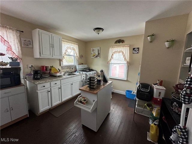kitchen with white cabinets, white gas range oven, black microwave, a sink, and dark wood finished floors