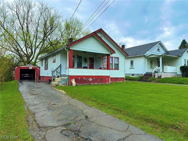 bungalow-style home featuring an outdoor structure, a porch, driveway, and a front yard