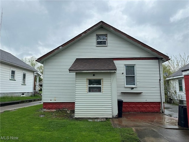 back of house featuring a yard and a shingled roof