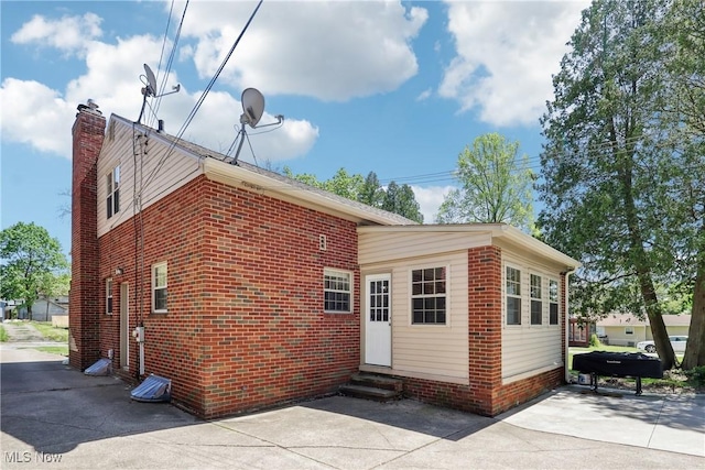 692 Roslyn Ave, Akron, OH 44320 - rear view of house featuring brick siding, a chimney, and entry steps