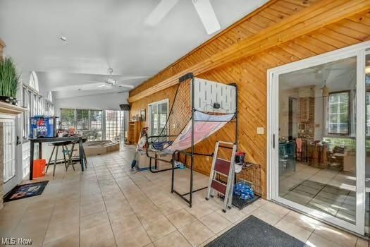 interior space with wooden walls, lofted ceiling, and tile patterned flooring