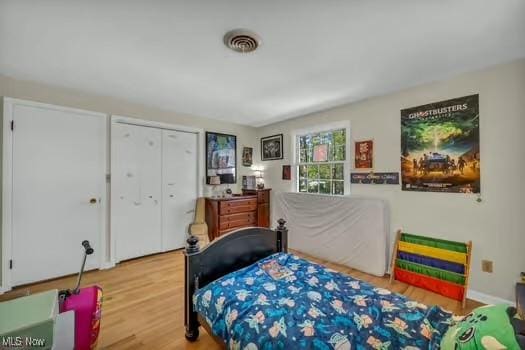 bedroom with visible vents, wood finished floors, and a closet